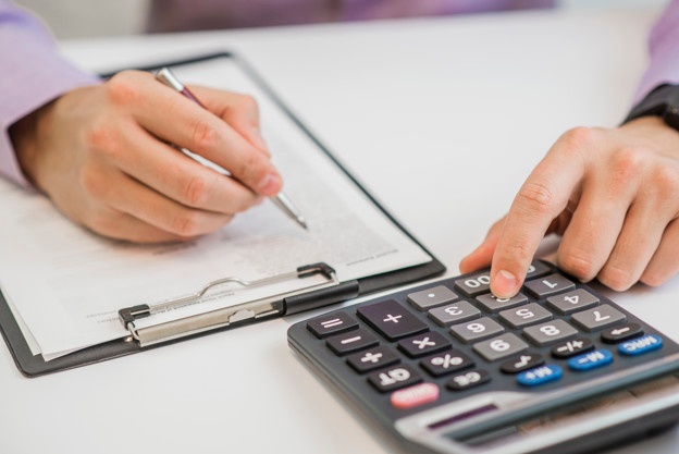 Close-up-businessman-calculating-invoices-using-calculator_1391-147
